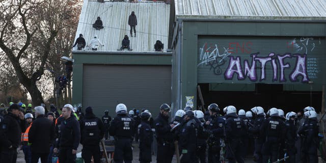 Activists who barricaded themselves in a barn sit on its roof after police entered the building at the settlement of Luetzerath in Germany.