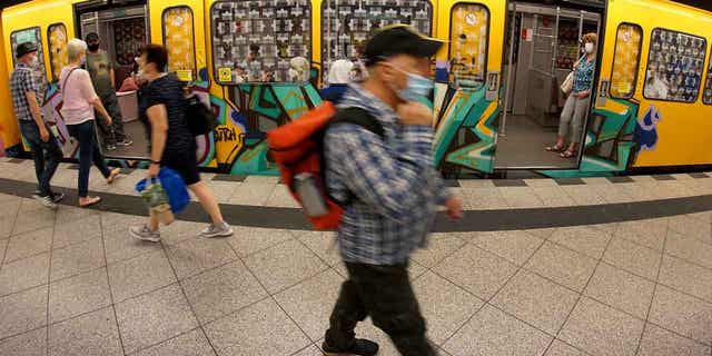 People wearing masks are shown boarding a subway train in Berlin, Germany, on June 23, 2020. Germany's health minister says the country plans to drop the mask mandate on long-distance trains and buses.