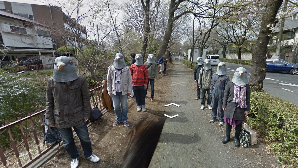 A bunch of people on the street in Japan are wearing bird hats.