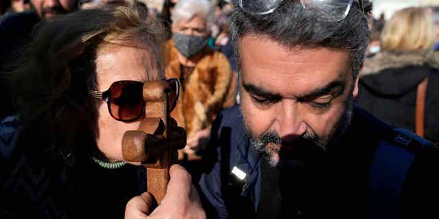 A woman kisses the cross during an Epiphany ceremony at a suburb in Piraeus port, near Athens, Greece, on Jan. 6, 2023. 