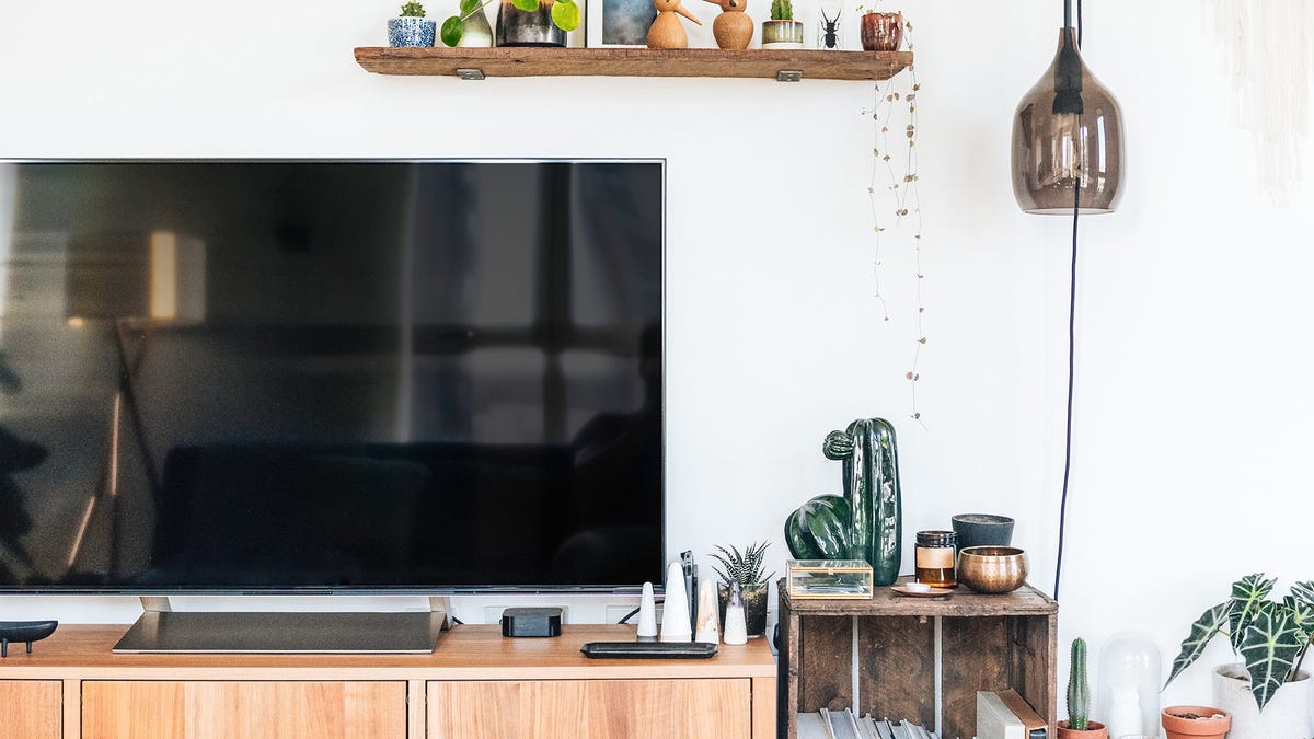 A TV on a stand against a wall of knickknacks. There are strong reflections on the TV.