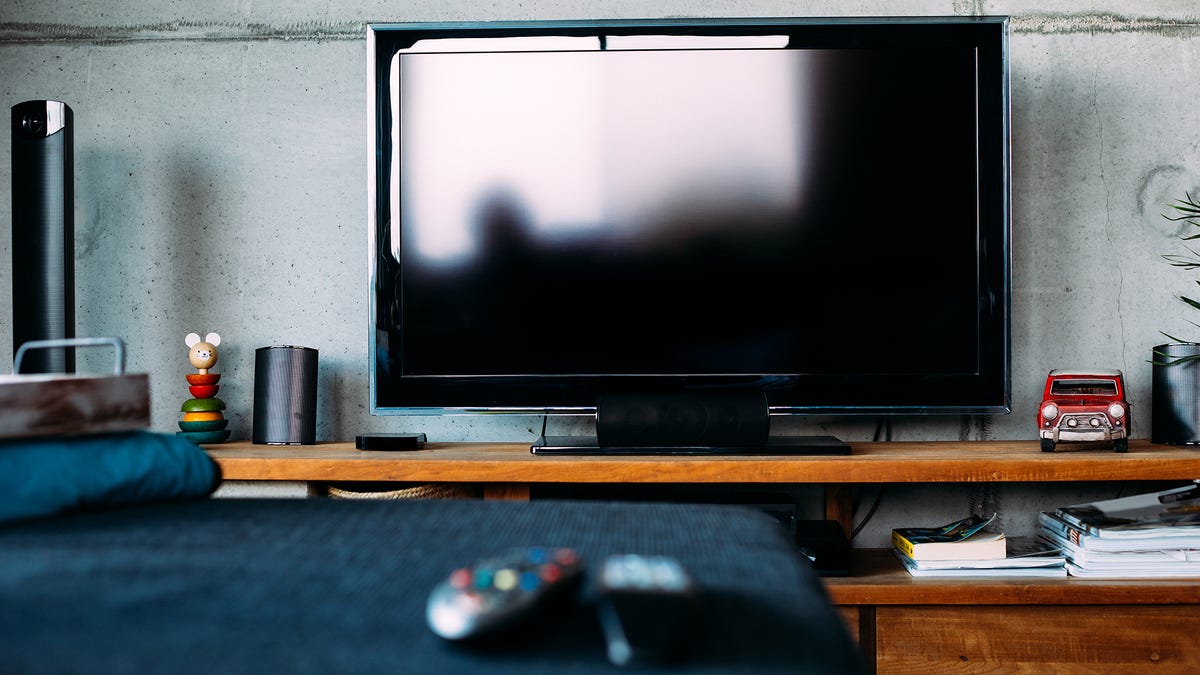 A small bedroom TV with a large reflection of a window.