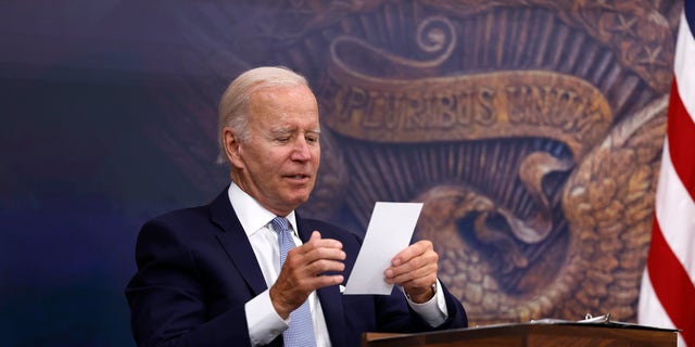 President Biden reads a note from an aide during a White House meeting on July 28, 2022. 