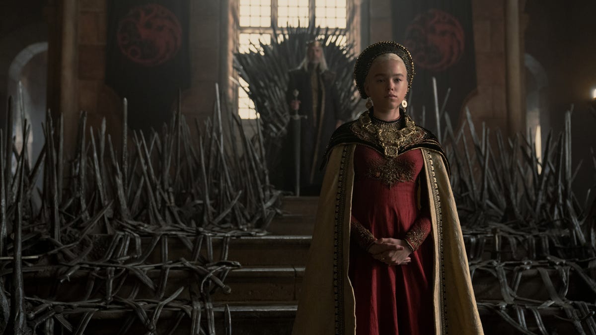 Princess Rhaenyra standing in front of the Iron Throne, with King Viserys sitting in it behind her