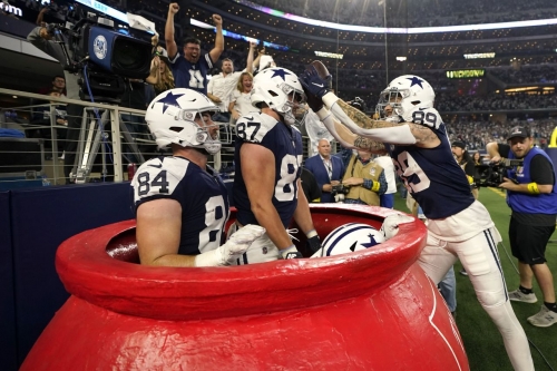 Dallas' Peyton Hendershot, right, celebrates a touchdown with teammates inside a big Salvation Army kettle during the Cowboys' Thanksgiving Day win over the New York Giants on Thursday, November 24.