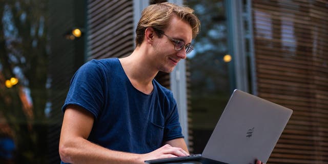 Man smiles at his Macbook