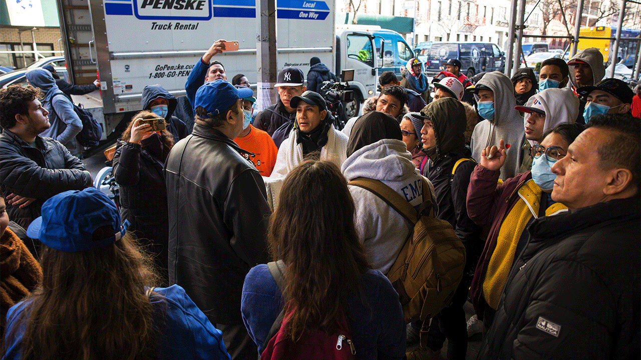 A member of the mayor's immigration office speaks with migrants who are camping out in front of the Watson Hotel after being evicted on Jan. 30, 2023, in New York City.