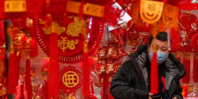 A man wearing a face mask shops for Chinese Lunar New Year decorations at a store in Beijing, Saturday, Jan. 7, 2023.
