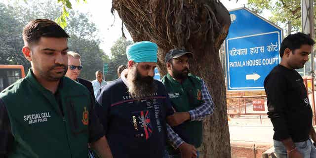 Policemen escort Rajwinder Singh, 38, after he was arrested in New Delhi, India, on Nov. 25, 2022. A court in New Delhi approved an extradition request for Singh, who is suspected of murdering a woman in Australia in 2018.