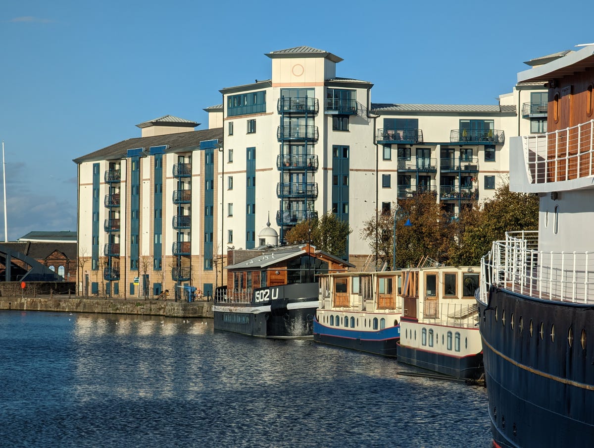 An image showing riverside buildings and moored narrowboats.