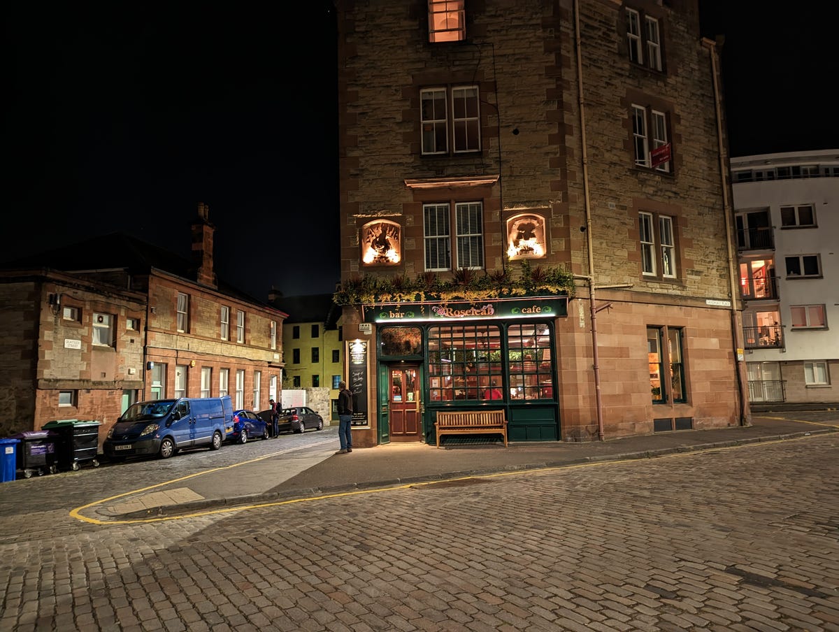 A night time image of a pub on a cobbled street.