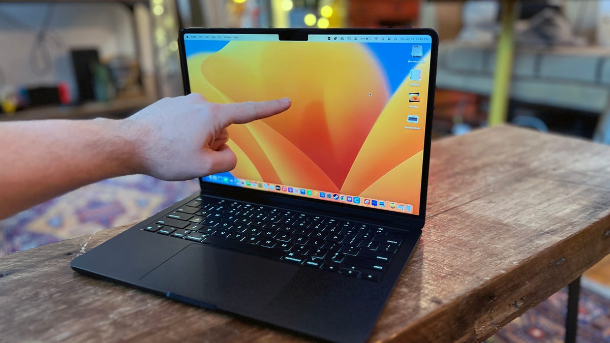 A finger touching a MacBook screen.
