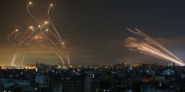 The Israeli Iron Dome missile defence system, left, intercepts rockets, right, fired by the Hamas movement towards southern Israel from Beit Lahia in the northern Gaza Strip as seen in the sky above the Gaza Strip overnight on May 14, 2021.