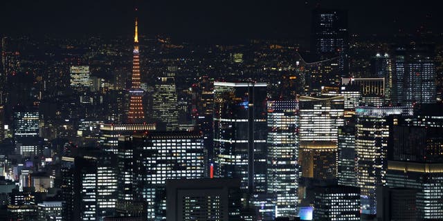 The illuminated Tokyo Tower, top left, among illuminated commercial and residential buildings at night in Tokyo.