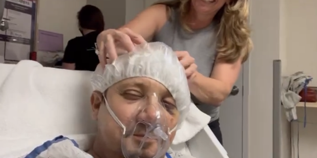 Renner is seen getting his head massaged while wearing a hairnet, breathing medical mask and lying down on the hospital bed. 