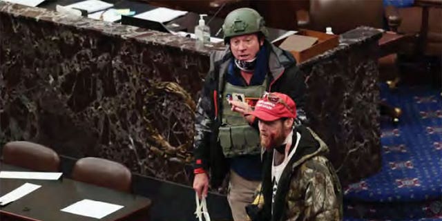 Joshua Black was seen on the Senate floor on Jan. 6, 2021 wearing a red hat, camouflaged jacket and yellow gloves. Blood is seen on his face after he was shot by a police projectile at the Capitol. 