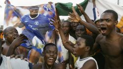 Abidjan, IVORY COAST:  Ivorian fans jubilate with a poster of star player Didie Drogba in a street in Koumassi, a poor neighborhood of Abidjan, after Ivory Coast qualified for both World Cup and CAN 2006 competitions 08 Ocotober 2005. AFP PHOTO / KAMPBEL.  (Photo credit should read KAMPBEL/AFP via Getty Images)