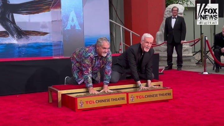 'Avatar' director James Cameron and producer Jon Landau dip their hands in wet cement for Hollywood ceremony