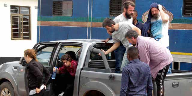 Seven of the eight Croatian nationals charged with attempting to traffic children exit a vehicle outside the magistrate's court in Ndola, Zambia, on Jan. 10, 2023. The Croatian nationals have pleaded not guilty to the charge of child trafficking.