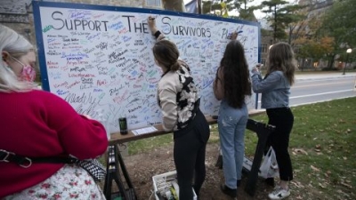  Attendees add their signatures to a board in support of survivors of sexual abuse at a vigil outside the home of outgoing University of Michigan President Mark Schlissel October 13, 2021 in Ann Arbor, Michigan. 