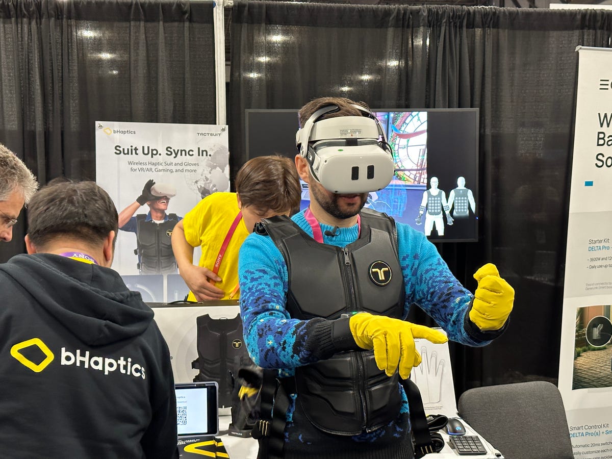 Someone with yellow gloves and a black vest wearing a VR headset