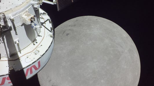 Gray moon looms large as Orion spacecraft appears on the left side in a partial view.
