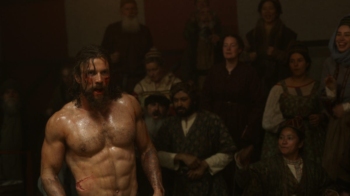 Leo Suter as Harald Sigurdsson, shirtless in a dark chamber with a crowd