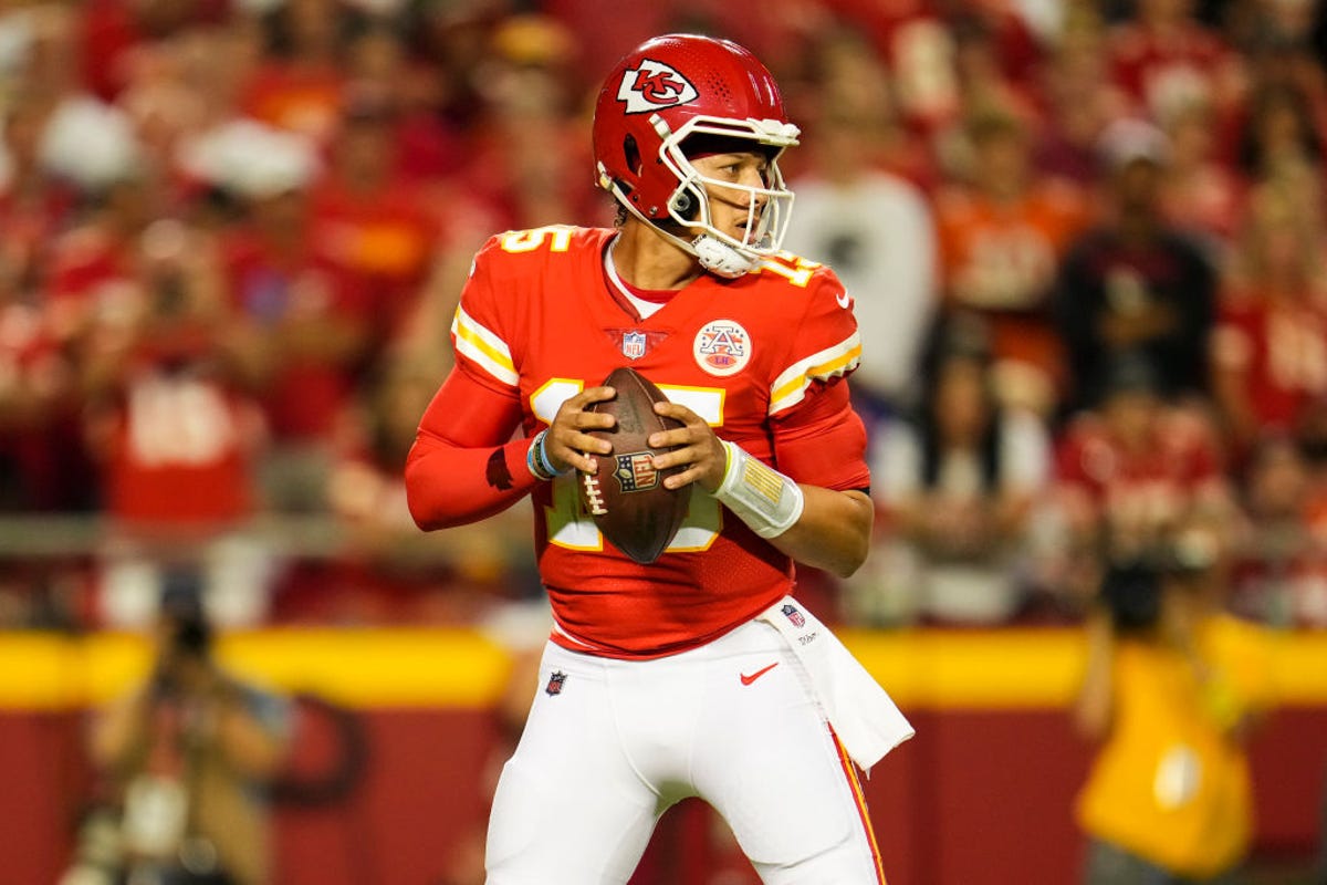 Patrick Mahomes, in red and white Kansas City Chiefs uniform, looks downfield