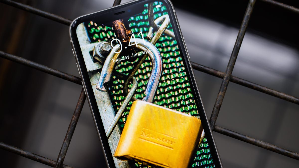 Image of an unlocked padlock on an iPhone screen in front of chain link fence