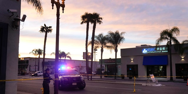 A police officer ties tape around a light pole in Monterey Park, Calif., Sunday, Jan. 22, 2023.