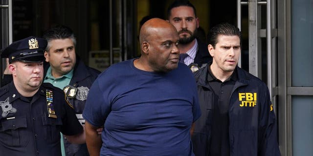 Law enforcement officials lead subway shooting suspect Frank R. James, 62, center, away from a police station, in New York on April 13. The man accused of shooting multiple people on a Brooklyn subway train faces multiple terrorism charges.