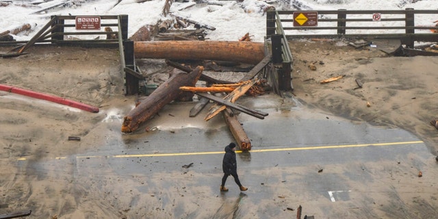 A California State Parks employee walks through a damaged road at Seacliff State Beach in Aptos, Calif., on Jan. 5, 2023. 