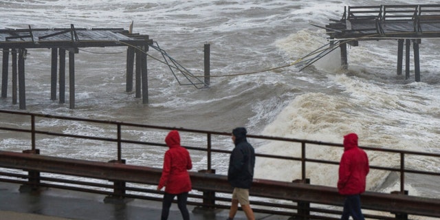 People walk along Cliff Drive to view the Capitola Wharf damaged by heavy storm waves in Capitola, Calif., on Jan. 5, 2023.