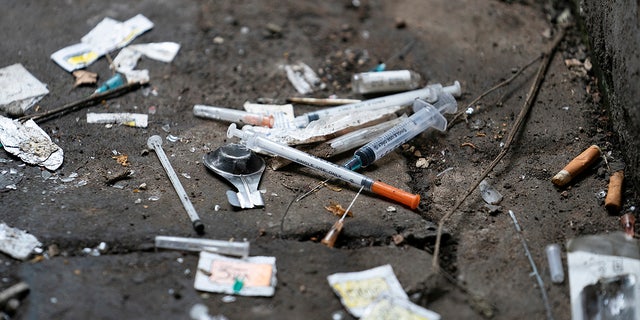 Syringes and paraphernalia used by drug users litter an alley.