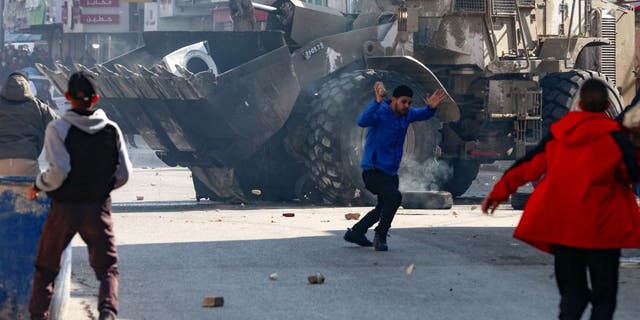 Palestinians hurl rocks at an Israeli army bulldozer, during confrontations in the occupied-West Bank city of Jenin, on January 26, 2023. (JAAFAR/AFP via Getty Images)