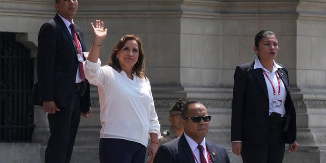 Surrounded by security, Peruvian President Dina Boluarte waves to the press outside the government palace as Prime Minister Alberto Otarola departs in Lima, Peru, Tuesday, Jan. 10, 2023. 