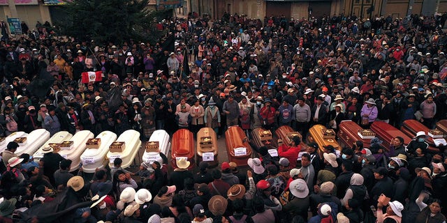 Residents surround coffins during a vigil for the more than a dozen people who died during the unrest in Juliaca, Peru, Tuesday, Jan. 10, 2023.