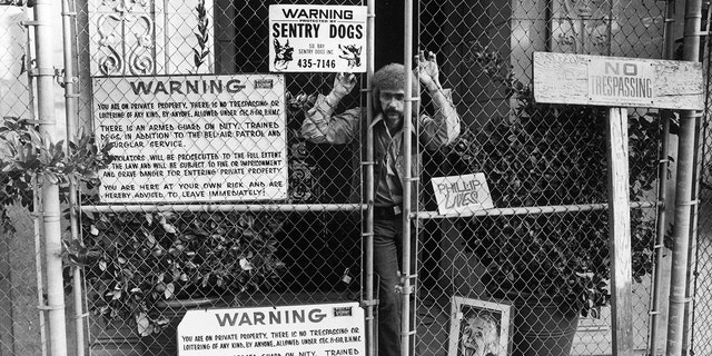 Record producer Phil Spector is seen here peering through the fence gates of his estate. On Feb. 3, 2003, the 62-year-old was arrested. He was later charged with murder in the shooting of actress Lana Clarkson.