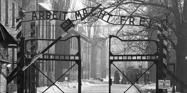 View of the main entrance to the Auschwitz concentration camp in Poland. The sign above the gate says "Arbeit Macht Frei" (Work makes one free).