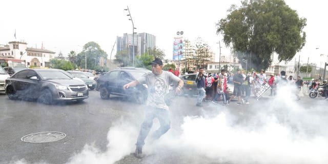 An anti-government protester throws a tear gas canister at the police during a march by demonstrators who traveled to the capital from across the country to protest against Peruvian President Dina Boluarte in Lima, Peru, Wednesday, Jan. 18, 2023.