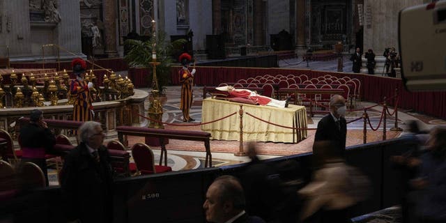 People look at the body of late Pope Emeritus Benedict XVI laid out in state inside St. Peter's Basilica at The Vatican, Monday, Jan. 2, 2023.