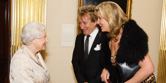 Queen Elizabeth II greets Sir Rod Stewart and wife, Penny Lancaster, after he was awarded a knighthood in recognition of his services to music and charity earlier in the day as they attend a reception and awards ceremony at the Royal Academy of Arts on October 11, 2016, in London, England. 