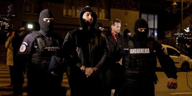 Andrew Tate and Tristan Tate are escorted by police officers outside the headquarters of the Directorate for Investigating Organized Crime and Terrorism in Bucharest (DIICOT) after being detained for 24 hours, in Bucharest, Romania, Dec. 29, 2022. 