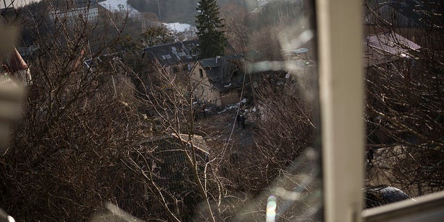 Damaged houses are seen through a broken window, following a Russian attack on New Year's Eve, in Kyiv, Ukraine, Monday, Jan. 2, 2023.