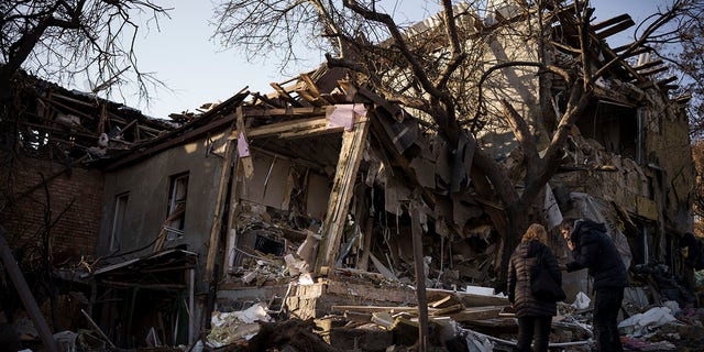 Serhii Kaharlytskyi, right, stands outside his home that was destroyed after a Russian attack in Kyiv, Ukraine, Monday, Jan. 2, 2023. Kaharlytskyi's wife Iryna died in the attack on Dec. 31, 2022.
