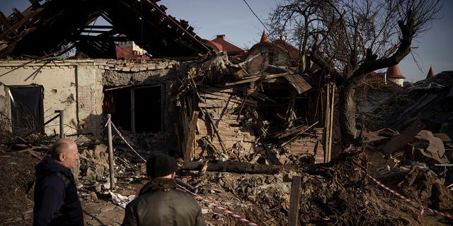 People stand next to the site of a Russian attack in Kyiv, Ukraine, Monday, Jan. 2, 2023.