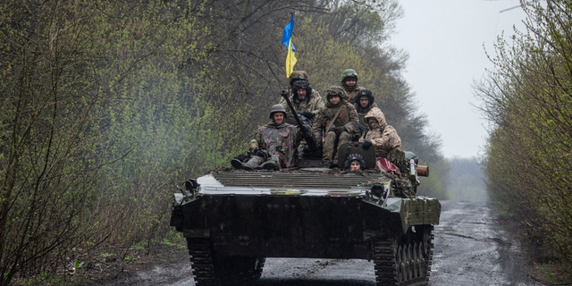 Ukrainian servicemen ride atop an armored fighting vehicle Tuesday as Russia's attack on Ukraine continues at an unknown location in Eastern Ukraine.