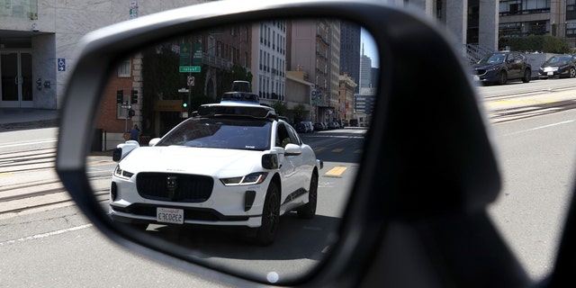 A Waymo autonomous vehicle is seen reflected in a mirror as it drives along California Street on April 11, 2022, in San Francisco, California. 