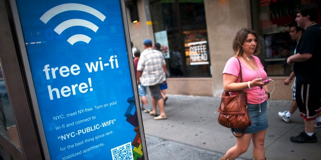 A woman walks past a WiFi-enabled phone booth in New York, July 12, 2012.