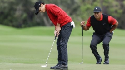 Charlie Woods putts while father Tiger watches on.